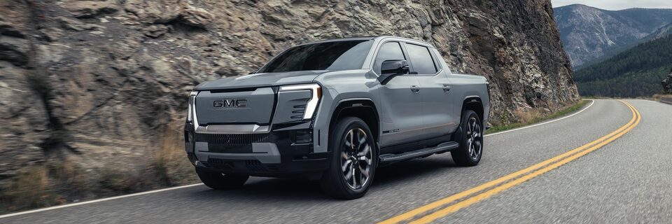 The GMC Sierra EV driving down a winding mountain road.