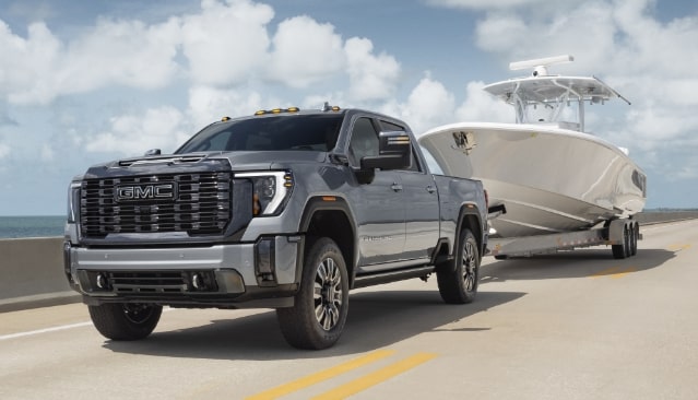 A Gray GMC Sierra HD Pickup Truck Towing a White Boat on a Trailer on a Coastal Highway