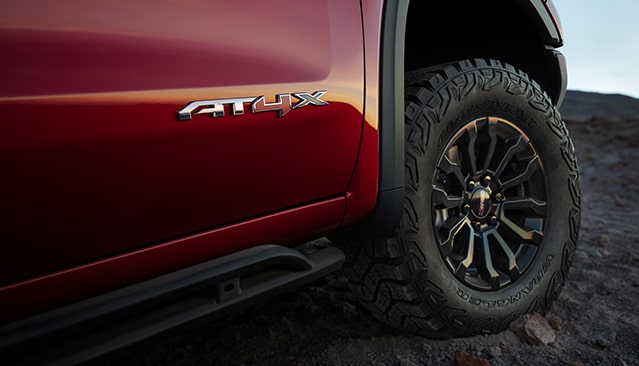 A Close-up of the AT4X Badge on the Red Fender of a GMC Sierra Pickup Truck With an Off-Road Tire