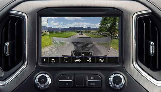 A GMC Vehicle Infotainment Screen Displaying a Rear Camera View of a Trailer Being Towed on a Rural Road