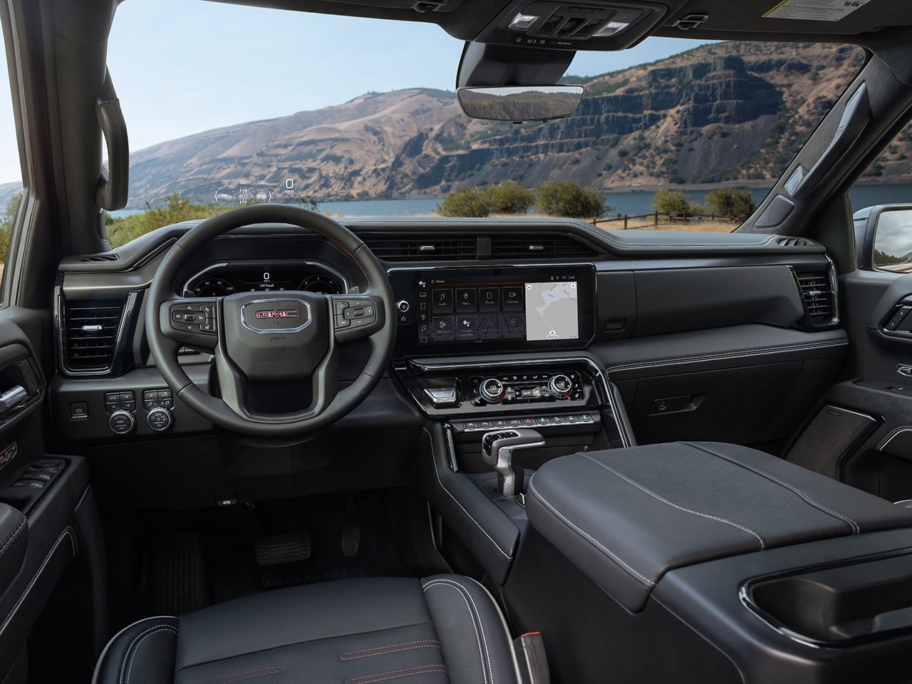Interior View of the Dashboard, Steering Wheel, and Infotainment System in a GMC Vehicle with a Beautiful Scenic Mountain View Through the Windshield