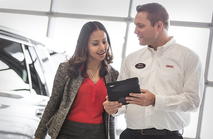Image of a man and a woman discussing a vehicle at a GMC Business Elite Dealer.