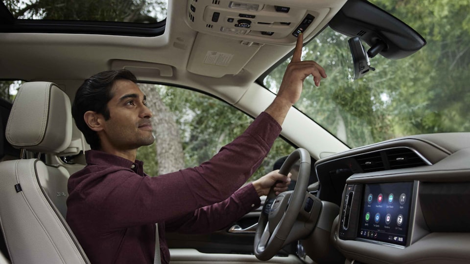 A Man Driving a GMC Vehicle Utilizing the OnStar Safety and Security Button