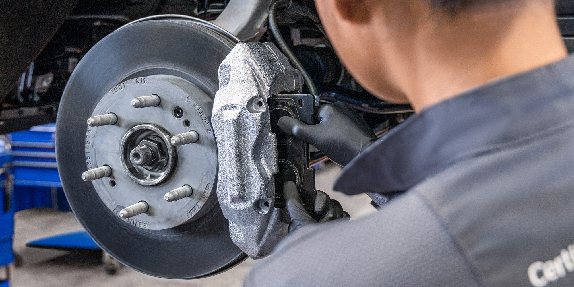A Mechanics Hands Are Seen Placing a Metal Break Rotor for a Vehicle