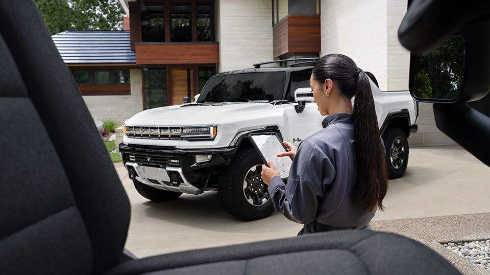 GMC Certified Service Technician Looking at a Tablet Standing Near a Hummer EV