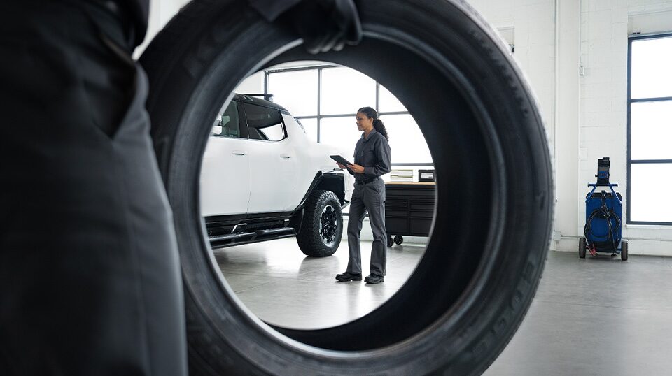 GMC Technician Working on a Vehicle With View Looking Through a Tire