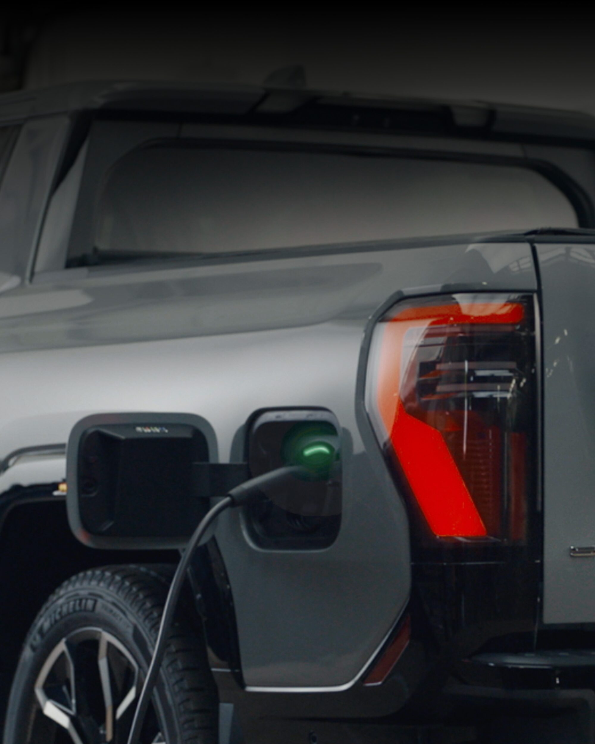 A Rear View of a GMC Sierra EV in a Dealership Room While Getting Charged.
