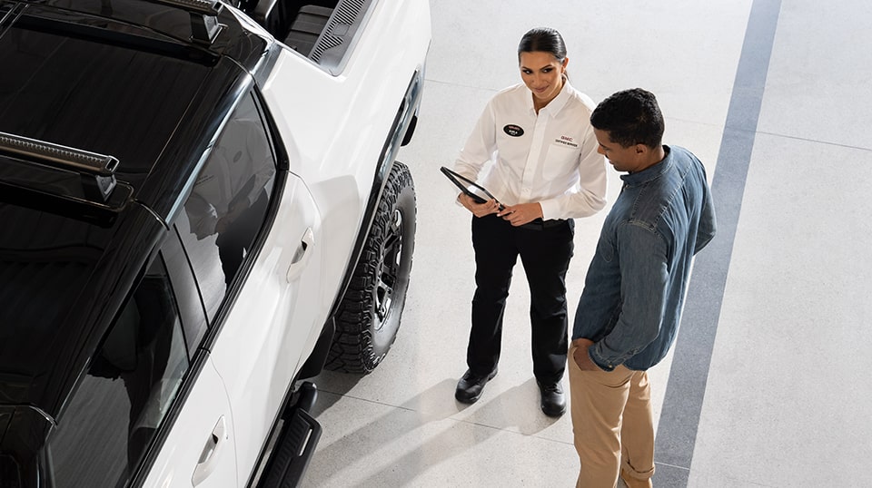 GMC Certified Service Representative Speaking with a GMC Hummer EV Trucker Owner Outside Their Vehicle