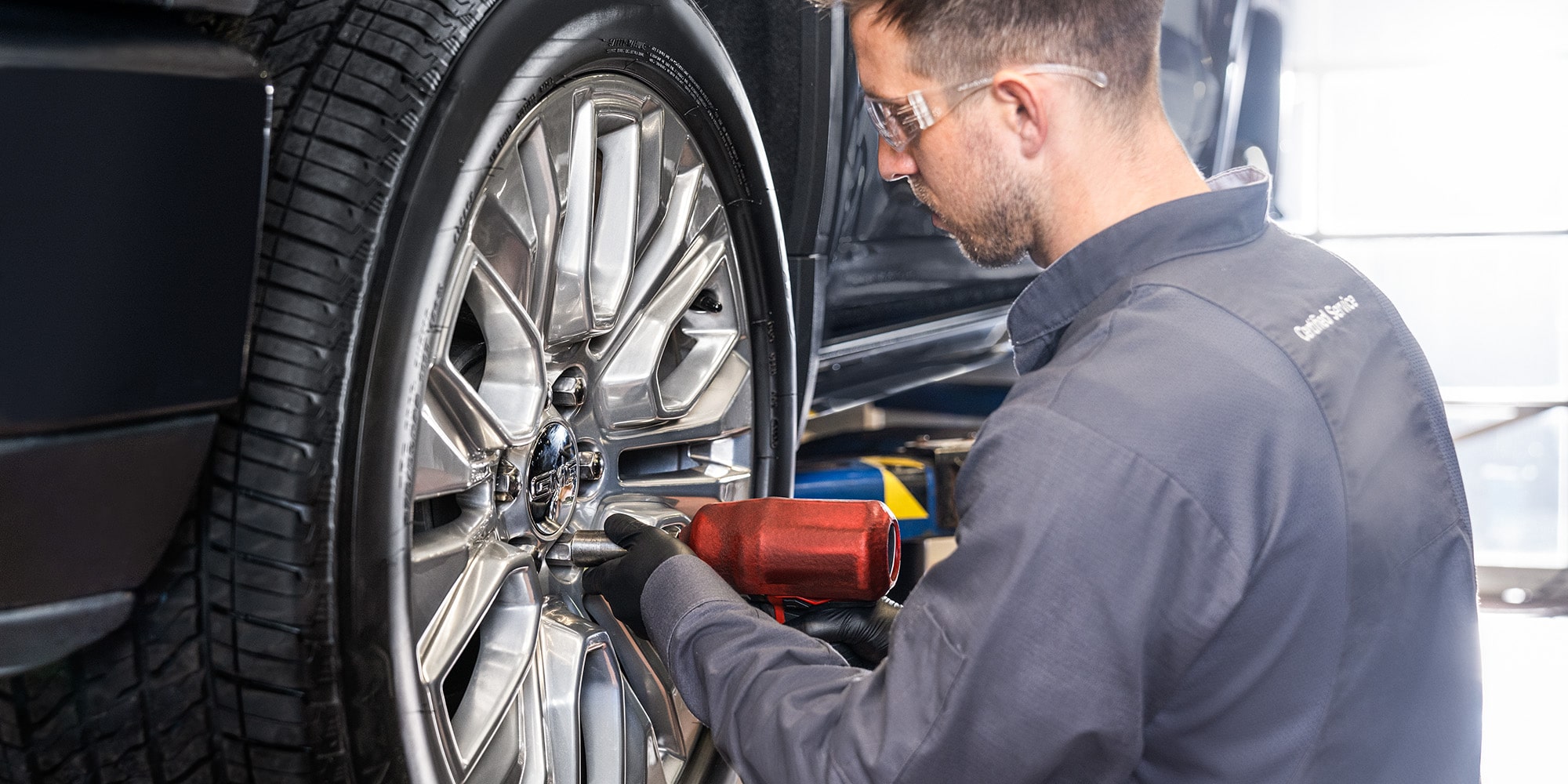 GMC Certified Service Technician Installing New Wheel on a Vehicle
