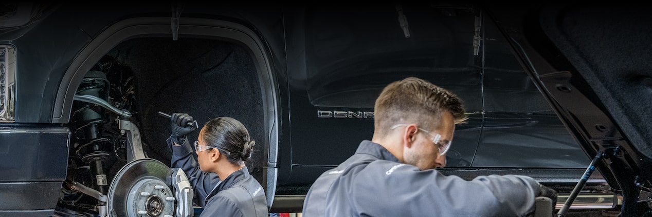A Woman and Man Service Technician in a Service Garage Working on GMC Vehicles.