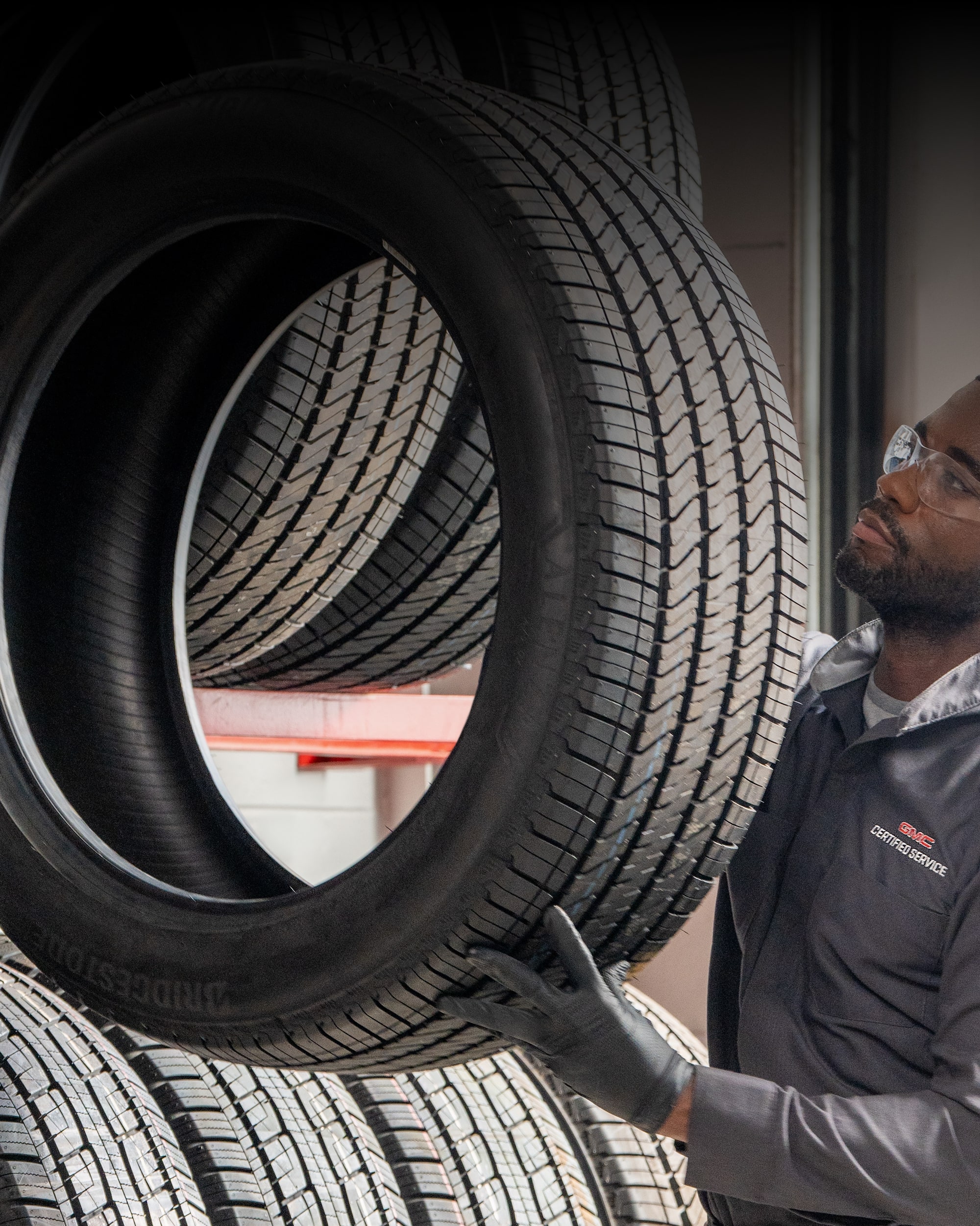 A GM Certified Service Technician Holding up a Tire.