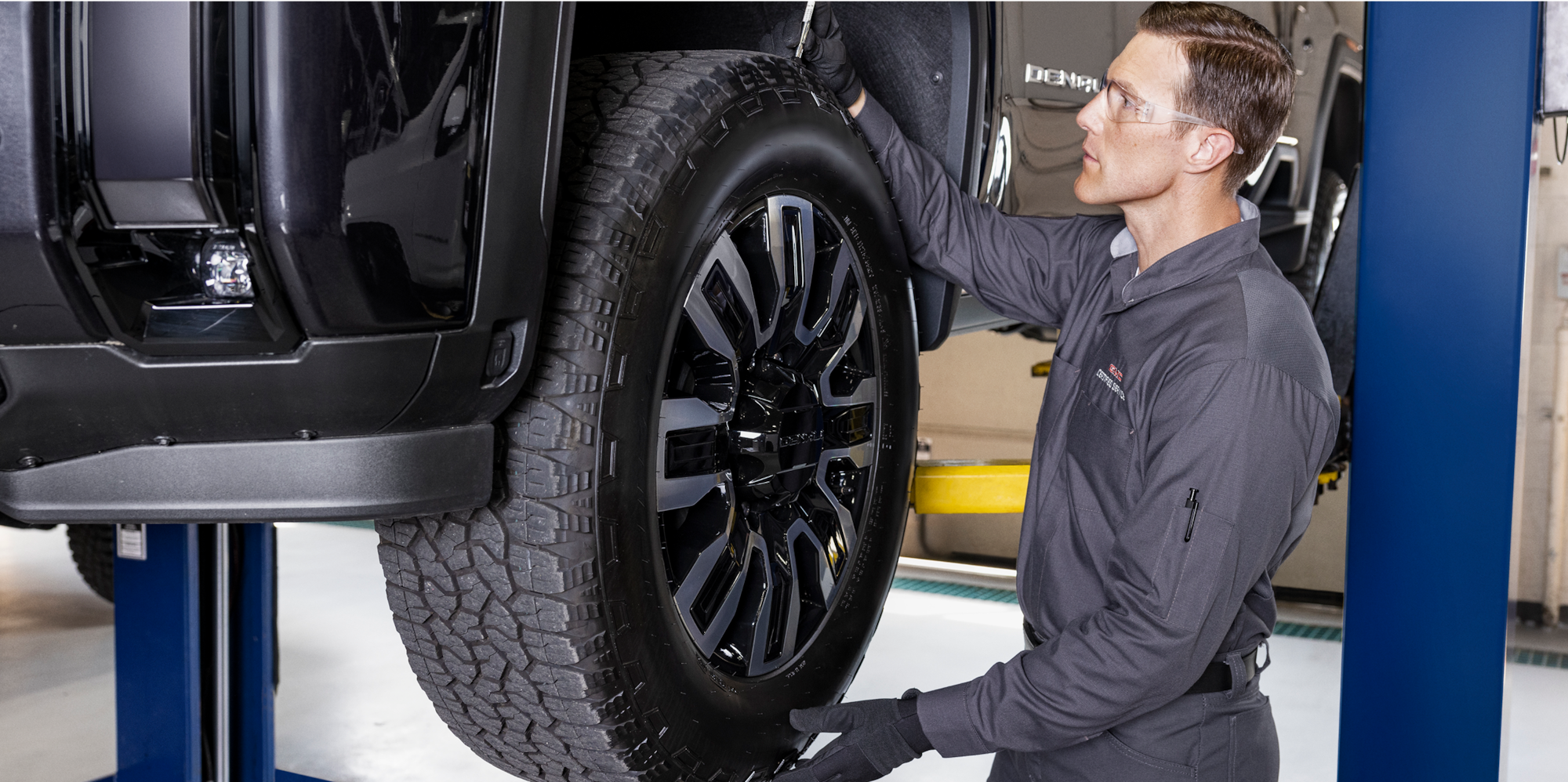 A Mechanic Is Changing the Tire of a Black GMC Vehicle