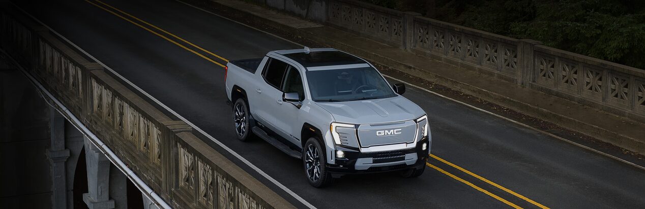 A White GMC Truck Driving Over a Bridge