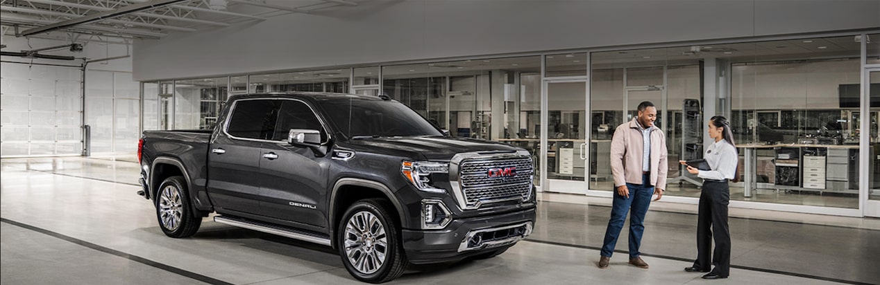 A Black GMC Truck on a Showroom Floor with Two People Standing Next to It