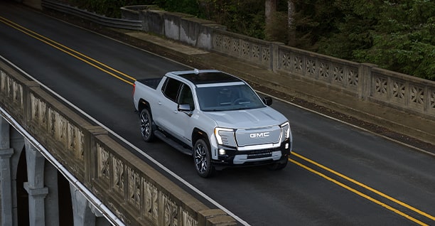 A White GMC Truck Driving Over a Bridge