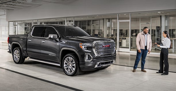 A Black GMC Truck on a Showroom Floor with Two People Standing Next to It