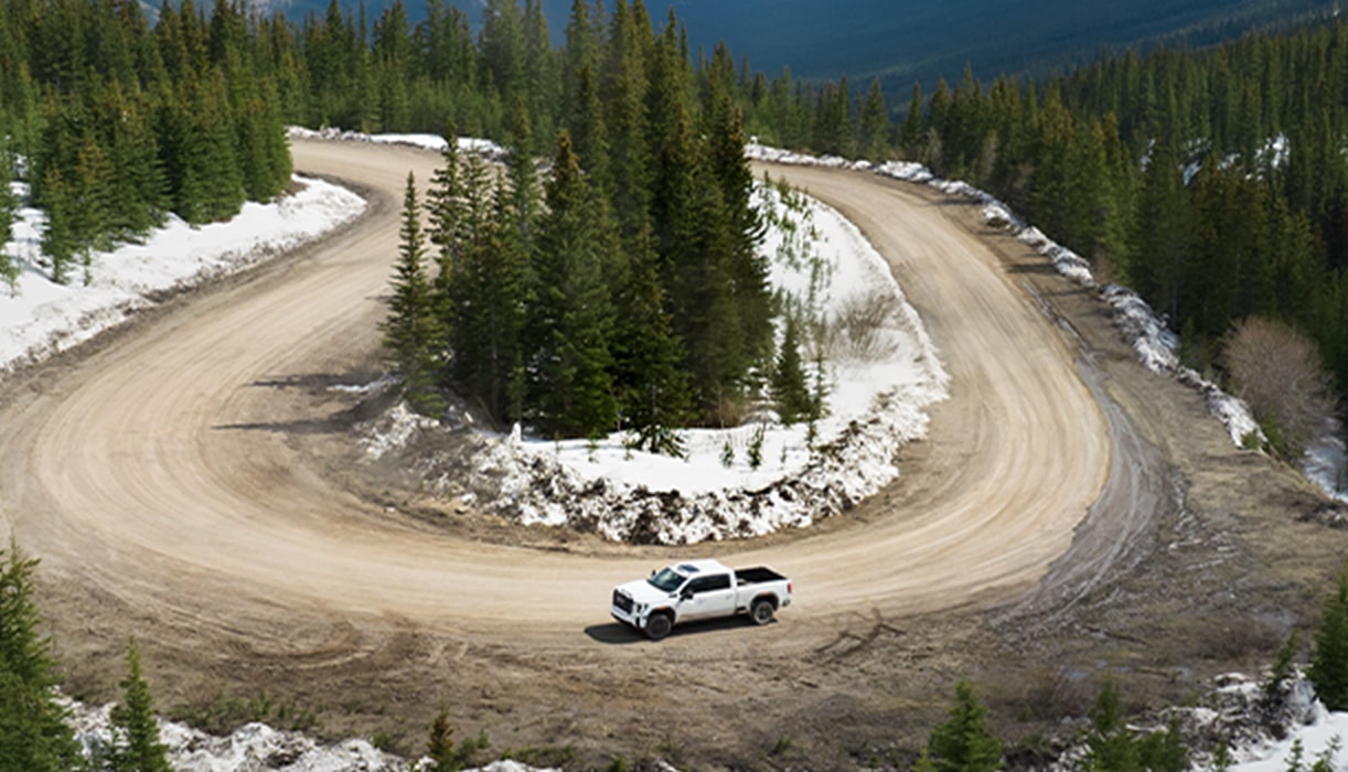 GMC Truck Driving on a Road Next to a Lake