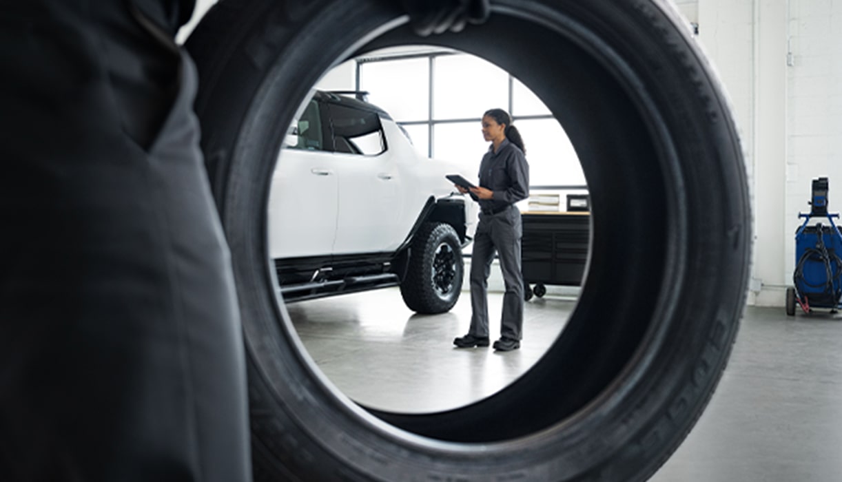 A White GMC Truck And Service Tech Framed Through Tire