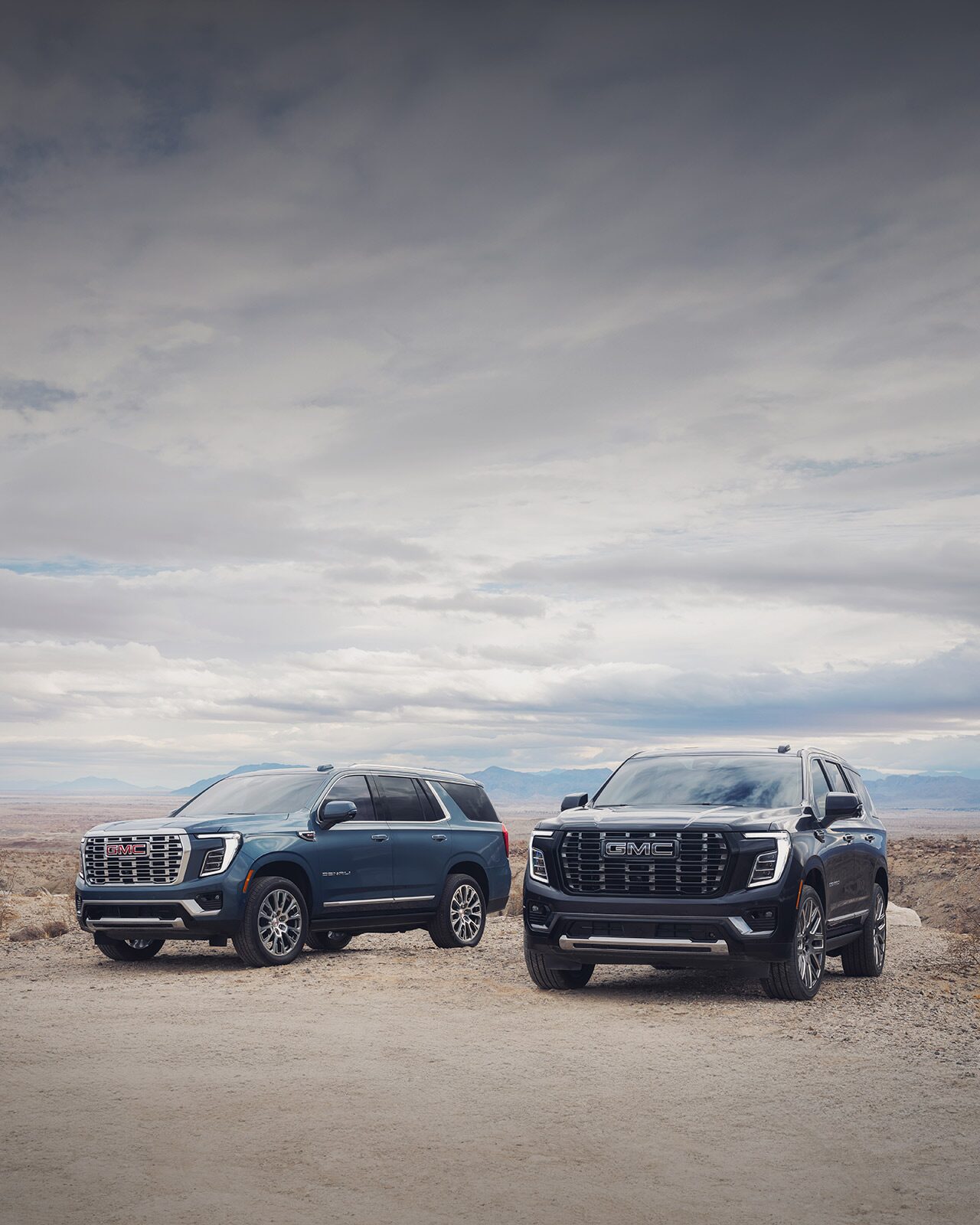 GMC SUVs Parked Side by Side in a Desert with Blue Skies in the Distance