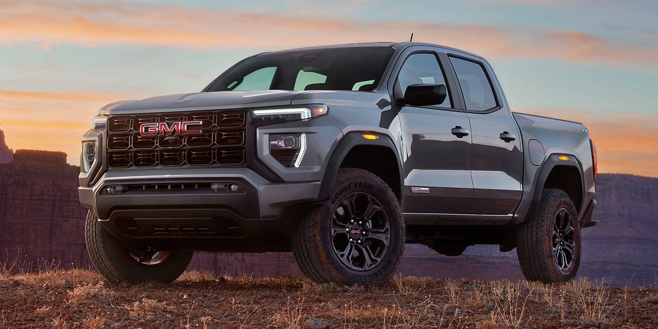 Front Three-Quarters View of the GMC Canyon Mid-Size Truck Parked in the Desert with a Beautiful Sunset Sky Above