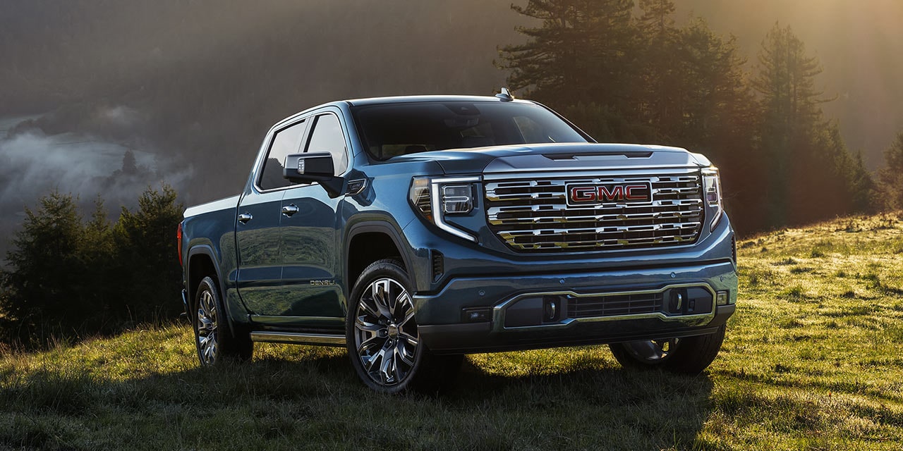 The GMC Sierra 1500 Pickup Truck Parked on a Grassy Hill as the Sunlight Shines Down on the Blue Truck