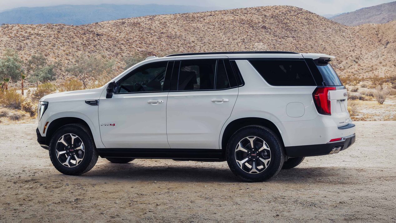 A White GMC Yukon AT4X Parked on a Dirt Road with Rocky Hills in the Background