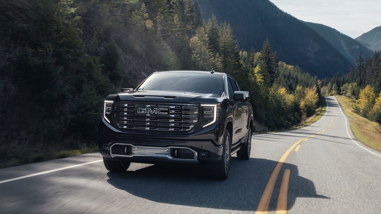 Front View of a GMC Sierra Driving Down a Tree Lined Paved Road
