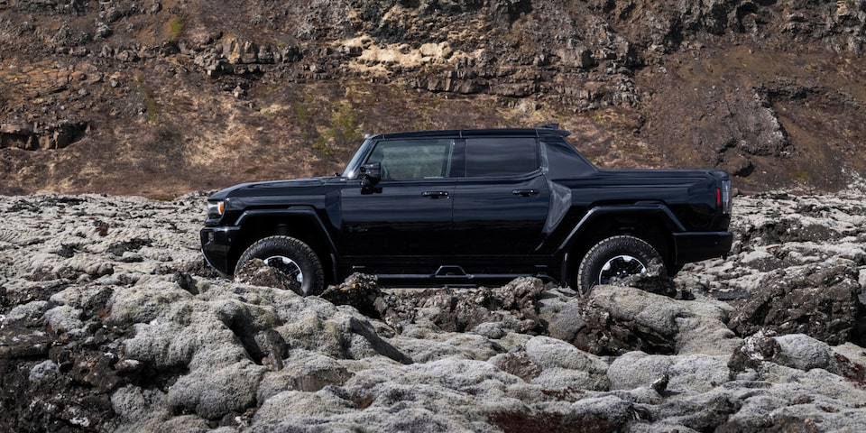 Side Profile View of a Black 2025 Hummer EV Pickup Truck Parked in the Rocky Mountains