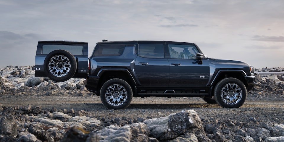 Side View of a Black GMC Hummer EV SUV  On a Rocky Plain with the Trunk Door Opened