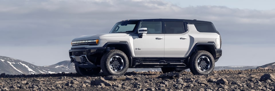 Side View of a White GMC Hummer EV SUV On a Rocky Plain under a Beautiful Blue Sky