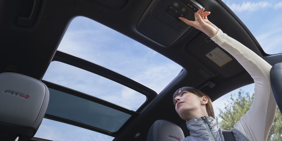 Interior View of the Driver Opening the Panoramic Sunroof in the GMC Acadia