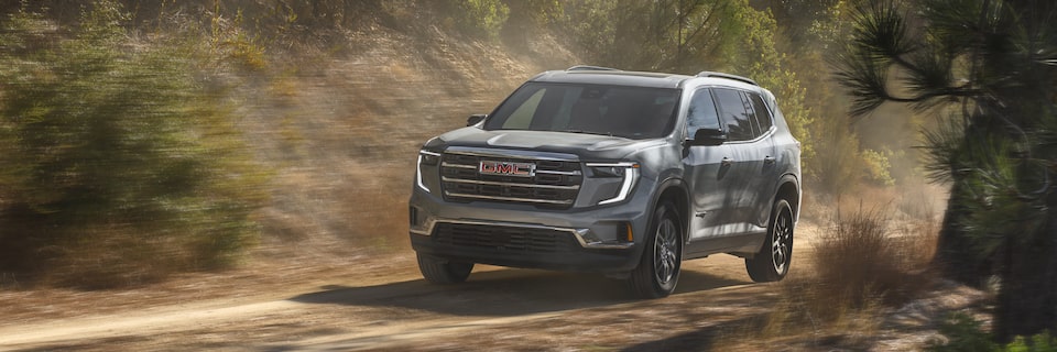 Front View of the 2025 GMC Acadia Driving Down a Dirt Road Through the Forest