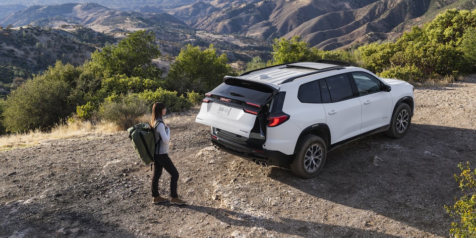 The GMC Acadia Mid-Size SUV Parked on a Mountain While the Driver Opens the Tailgate