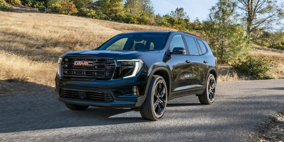 GMC Acadia Mid-Size SUV Driving Down a Road with Blue Skies