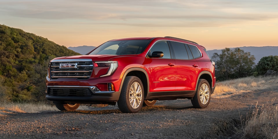 A Red GMC Acadia Parked on a Dirt Road