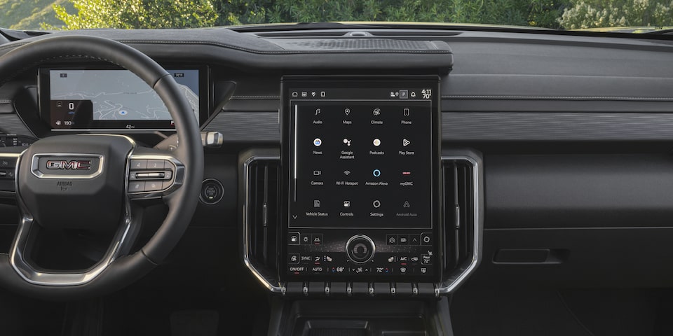 Close-up Interior View of the GMC Acadia Steering Wheel, Infotainment System, and Dashboard