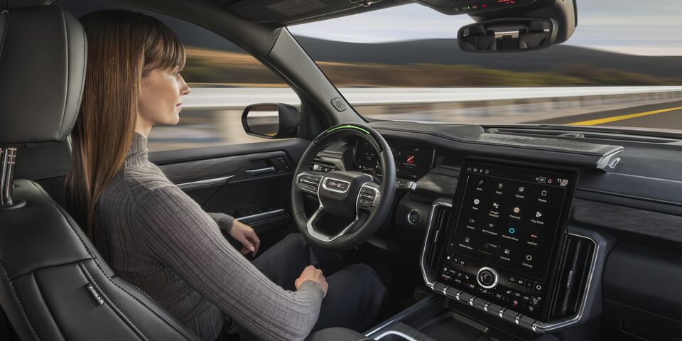 A Woman Sitting in the Drivers Seat of the GMC Acadia AT4 SUV Using Super Cruise Hands-Free Driving Technology