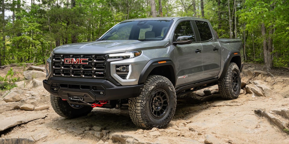 Three-quarter View of a 2025 GMC Canyon Truck Parked on Dirt with Trees in the Background