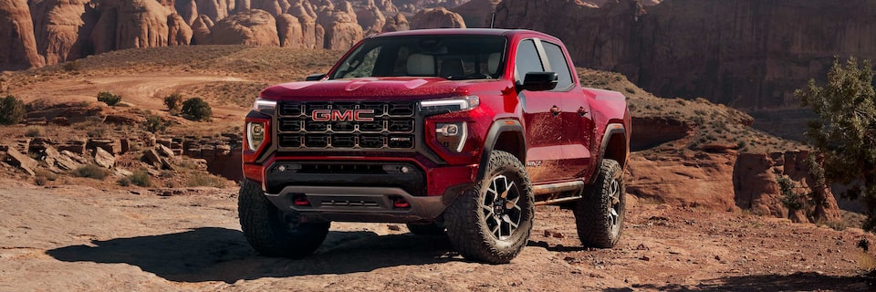 Three-quarters View of a Red 2025 GMC Canyon AT4 Parked on a Rocky Desert Trail After Off-roading