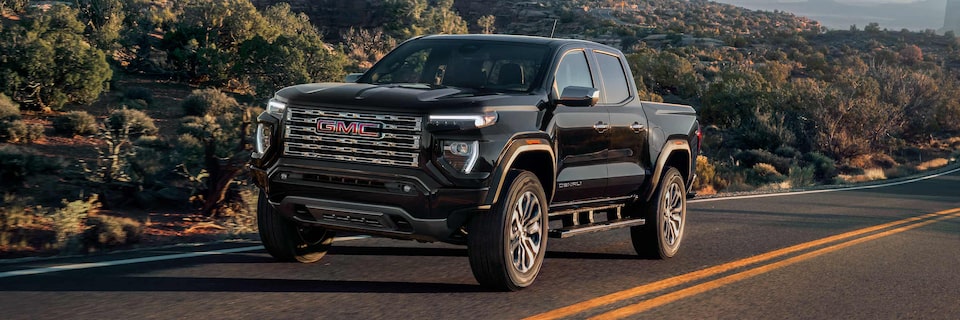 Three-quarter View of a 2025 GMC Canyon Denali Driving Down a Mountain Road