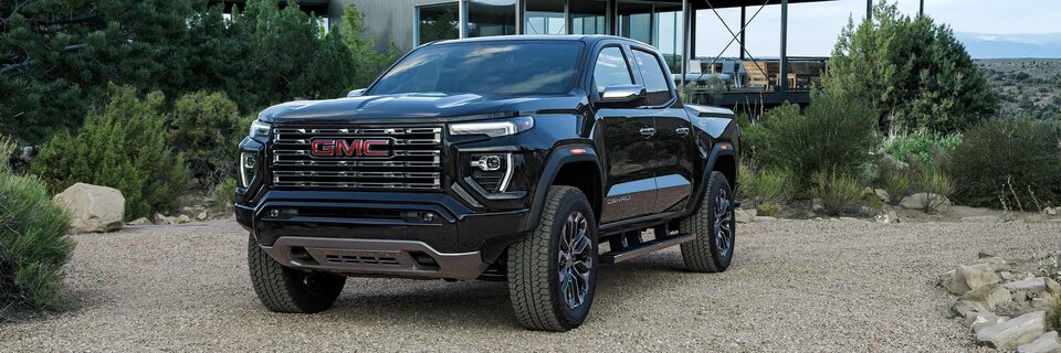 Three-quarter View of a 2025 GMC Canyon Denali Parked Outside of a Modern Mountain Cabin