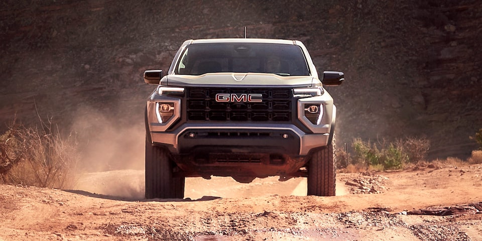 Front View of a 2025 GMC Canyon Off-roading Through the Desert While Kicking Up Dirt