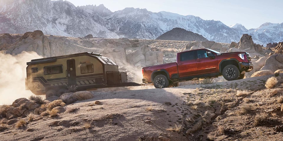 Side View of a 2025 GMC Sierra HD AT4 Truck Hauling a Small Trailer Through the Mountains