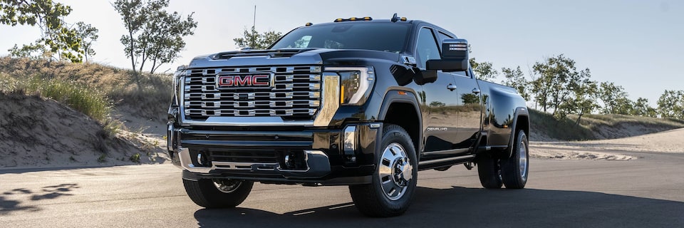 Wide Front Three-Quarters View of a 2025 GMC Sierra HD Denali Truck Driving on an Open Road