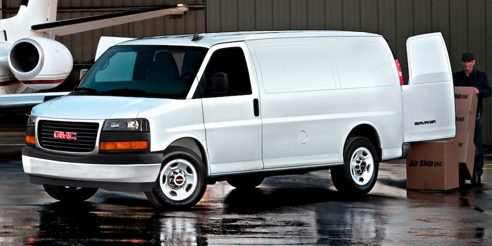 A White GMC Savana Cargo Van Parked Next to a Jet