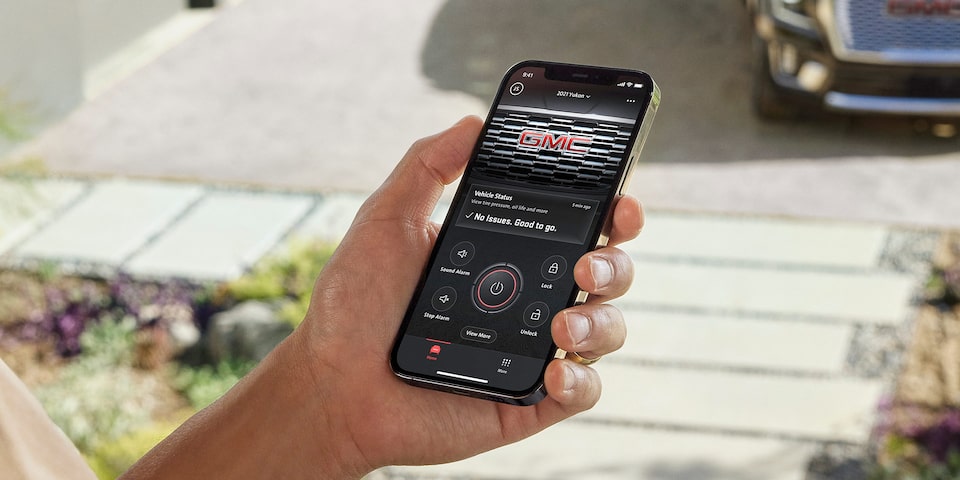A Person Holding a Smartphone with the myGMC App Open Showing Vehicle Health and Specs
