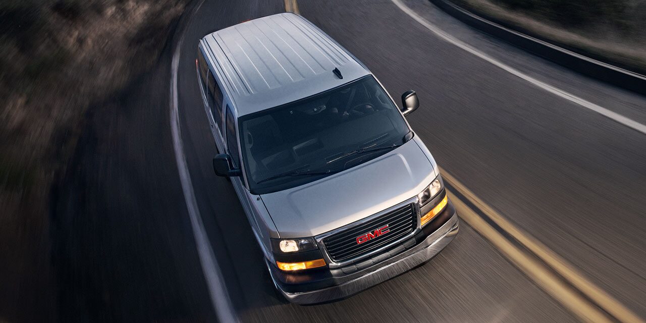 Birds-eye View of a 2026 GMC Savana Passenger Van Driving on an Empty Road at Night