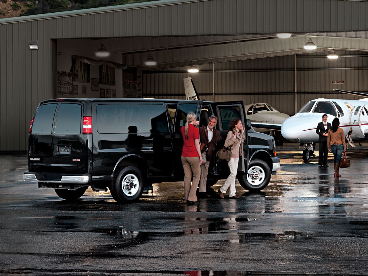 A Woman Helping a Couple out of a Black GMC Savana Passenger Van