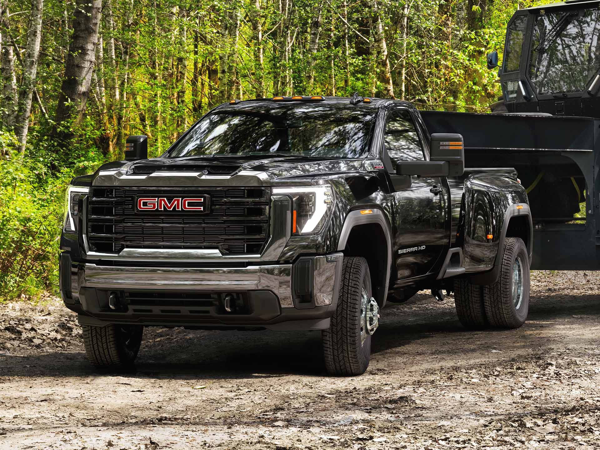 Front Three-Quarter View of the 2026 GMC Sierra Chassis Cab Work Truck Driving Down a Dirt Road