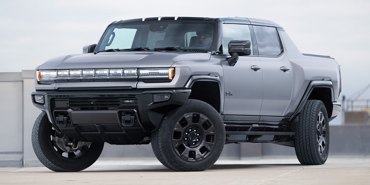 Front Three-Quarters View of the GMC HUMMER EV Pickup Truck Parked by a Concrete Wall